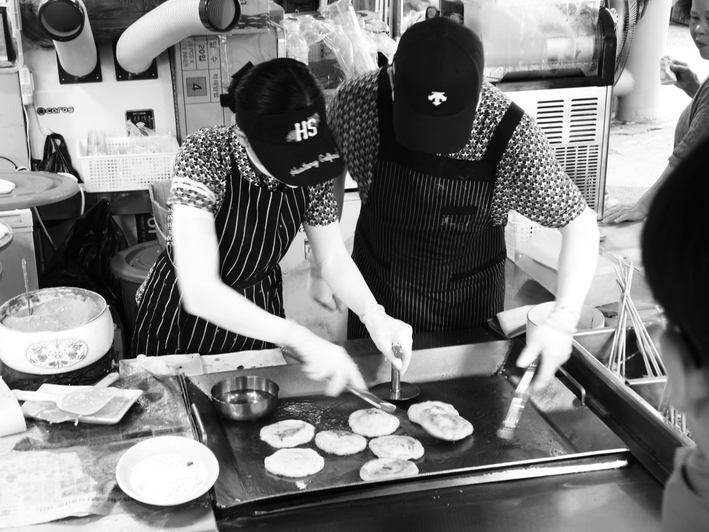 Workers make hoetteok or korean sweet pancake at a market